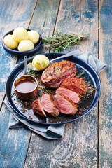 Traditionell gegrilltes Gourmet Entenbrust Filet mit Haut serviert mit Kartoffelknödel in Dunkelbier Sauce als Draufsicht auf einem rustikalen Metall Tablett