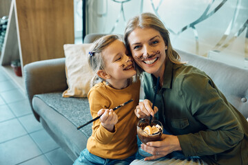 Happy mother and daughter with chocolate mousse mustache.
