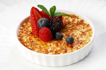 Creme brulee, caramel crust dessert with red berries, burnt cream close up view