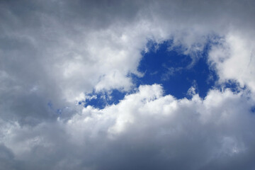 Hole in the cloud. Glimpse of the sky in the clouds. Blue sky breaking through the clouds. A...