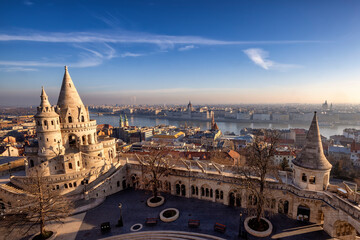 Fototapeta premium Panorama of the Fisherman's Bastion (Halaszbastya) from above with Hungarian Parliament building and River Danube at background during a golden sunrise morning in Budapest