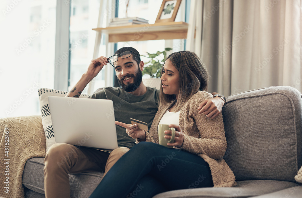 Poster a happy customer is a comfortable customer. shot of a young couple using a laptop and credit card on