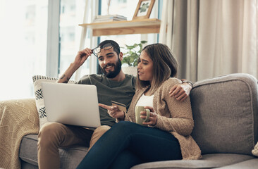 A happy customer is a comfortable customer. Shot of a young couple using a laptop and credit card on the sofa at home.