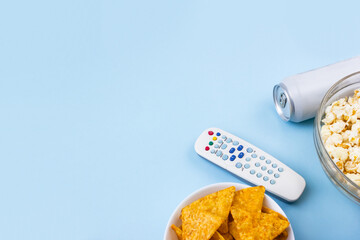 Remote control, popcorn, can of beer and nachos on blue background. Concept of family watching...