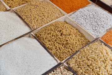 Variety organic groats in box on sale on a farmers market, ecological cereal products, pasta, lentils. Food background