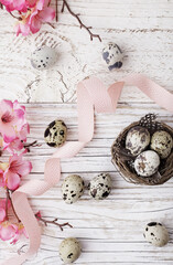 easter quail eggs and flowers on wooden background