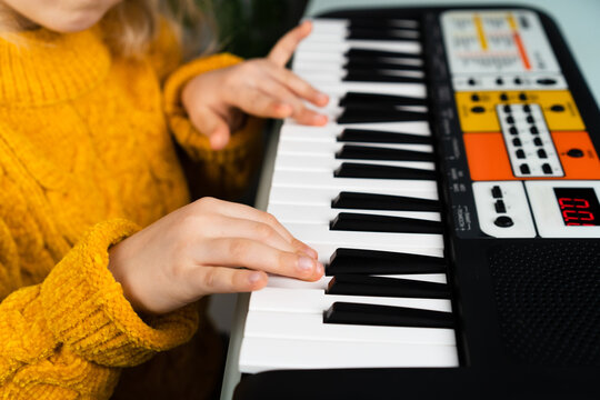 a little girl playing the synthesizer, the concept of teaching children music, hands close-up