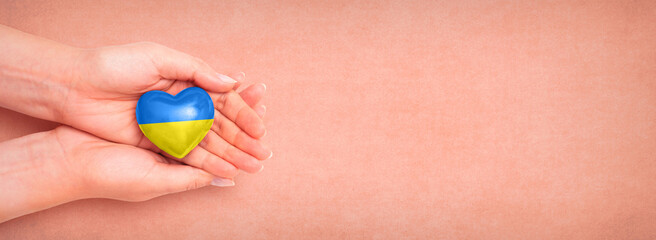 Hand holding a heart with Ukrainian national colors. Help Ukraine during the war