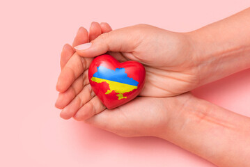 Hand holding a heart with Ukrainian national colors. Help Ukraine during the war