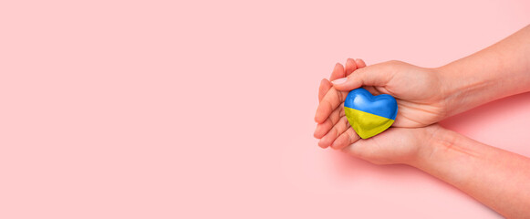 Hand holding a heart with Ukrainian national colors. Help Ukraine during the war
