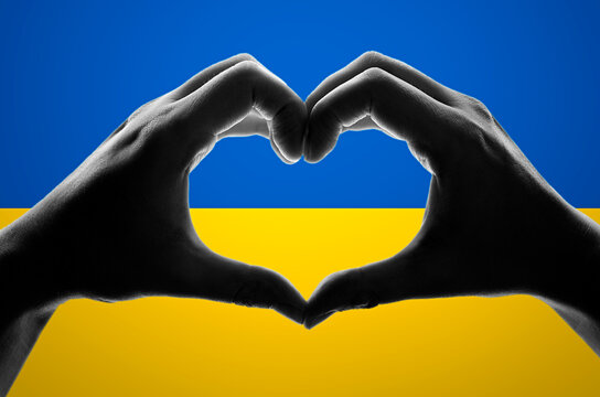 Hands in heart shape on the Ukrainian flag. Help Ukraine during the war
