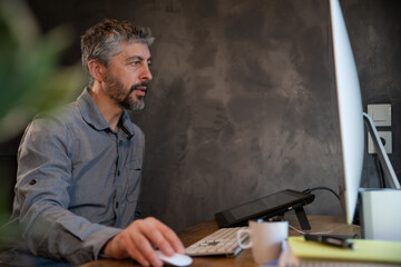 portrait d'un employé de bureau souriant ou d'un homme d'affaire assis à son bureau en train de travailler. Il travaille sur un ordinateur à la maison