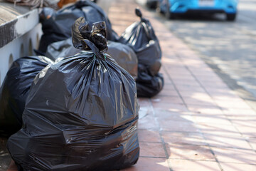 Pile of black plastic bags that contains garbage inside on the floor. Waiting for the rubbish keeper officers to take them away. Concept : Waste management. Collected for disposal.                    