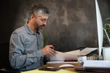 portrait d'un employé de bureau souriant ou d'un homme d'affaire assis à son bureau en train de travailler. Il travaille sur un ordinateur à la maison