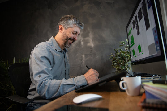 info graphiste, dessinateur ou employ&eacute; de bureau souriant utilisant une tablette graphique pour dessiner ou travailler dans son bureau