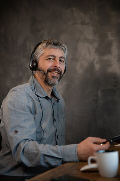 portrait d'un employ&eacute; de bureau souriant qui communique avec un micro casque et un ordinateur dans son bureau. Il travaille &agrave; la maison &agrave; distance gr&acirc;ce &agrave; internet.