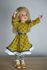 doll with long blond hair in smart clothes, in ayellow dress and boots, concept children's toy, doll fashion, hobby, for girls, happy childhood