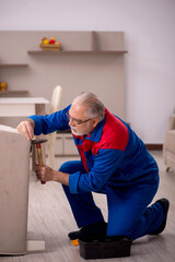 Old male carpenter working indoors