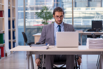 Young male employee in wheel-chair working in the office