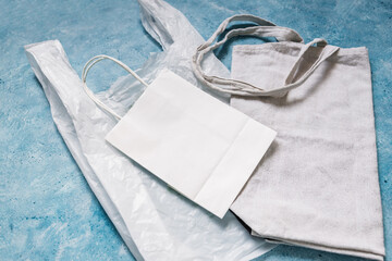 single use plastic bag next to paper and reusable canvas ones, plastic pollution and environmental awareness