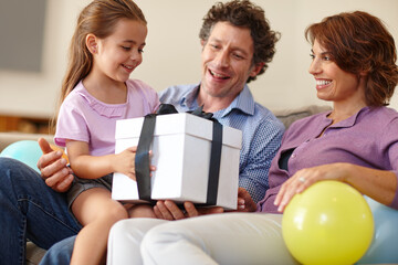 Family is a gift that lasts forever. Shot of a family siting in the living room with a gift.