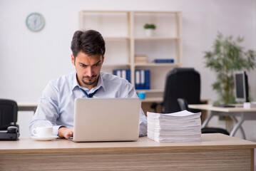 Young male employee unhappy with excessive work in the office