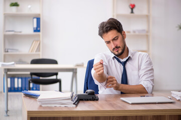 Fototapeta premium Young male employee unhappy with excessive work in the office