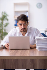 Young male employee and too much work in the office