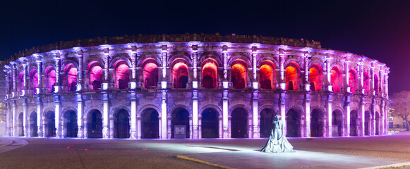 Panoramic view of colorful lighted Arena of Nimes at dusk, France