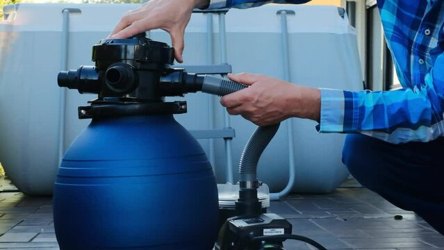 Swimming pool Filter.Blue water filter in the hands of a man in a blue plaid shirt on a blue pool background. Swimming pool cleaning equipment.A man moves the hoses to the filter in the pool close-up