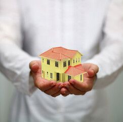 hand holding miniature house. housing loan concept