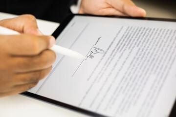 Close up businessman hand electronic Signature on Tablet by Stylus. Write business agreement of contract. Man signing contract on tablet. Business and technology concept.