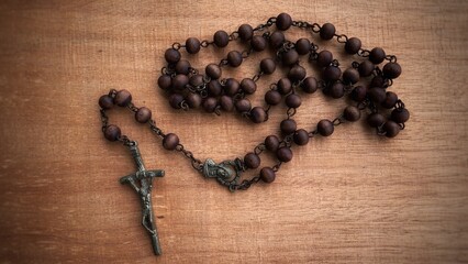 Top view of Holy Rosary on wooden table. Christianity concept.