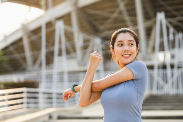 Beautiful asian woman wearing sportswear warming up front of sport stadium. Confident and powerful...