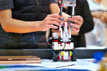 Close up of school students building and testing robot vehicle project model in robotics class for the competition. Science, technology, innovation, creativity, education STEM background.