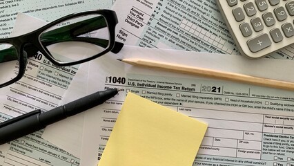 1040 US individual tax form, pen, yellow sticker, pencil calculator and pen.