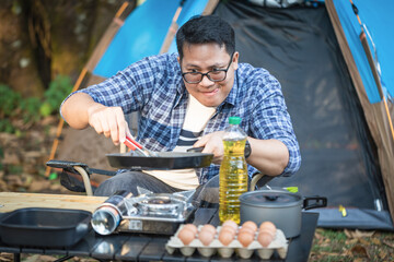 Young male cooking alone outdoor camping with a tent.