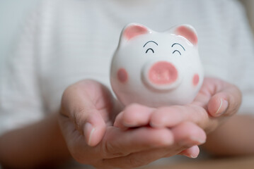 Hands holding piggy bank. Saving concept with piggy bank indoor