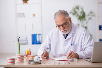 Old male doctor dentist working in the clinic