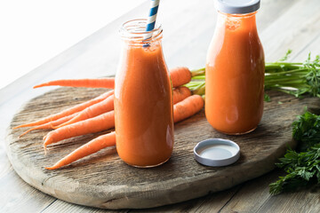 Bottles of healthy carrot juice with bright light coming in from behind.