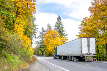 Bonnet long haul big rig blue semi truck transporting cargo in reefer semi trailer driving on the...