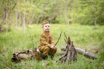 a small child in a beautiful military victory uniform, playing in nature and eating soldier porridge