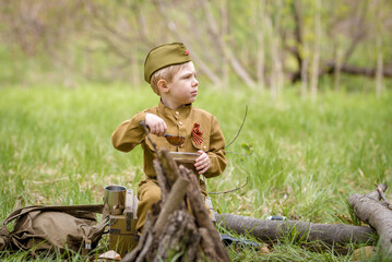 a small child in a beautiful military victory uniform, playing in nature and eating soldier porridge