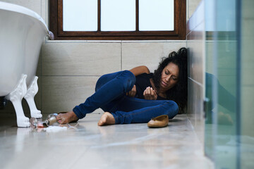 Dependent on drugs. Shot of a drug addict passed out on the bathroom floor. - obrazy, fototapety, plakaty