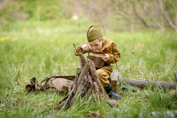 a small child in a beautiful military victory uniform, playing in nature and eating soldier porridge