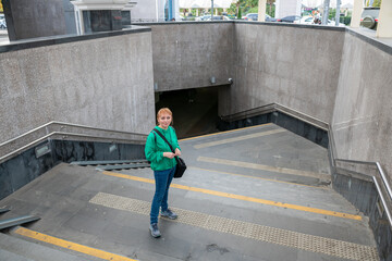 A confused girl is standing on the stairs of the underpass.