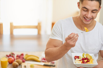 Nothing beats waking up to a healthy breakfast. Cropped shot of a young man eating a fruit salad.