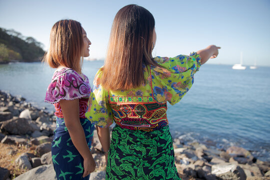 two women guna standing on the beach