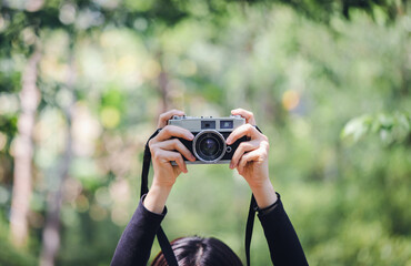 Female hand holding digital camera green nature bokeh background