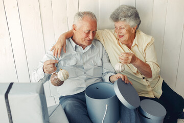 Elegant old couple sitting at home with christmas gifts